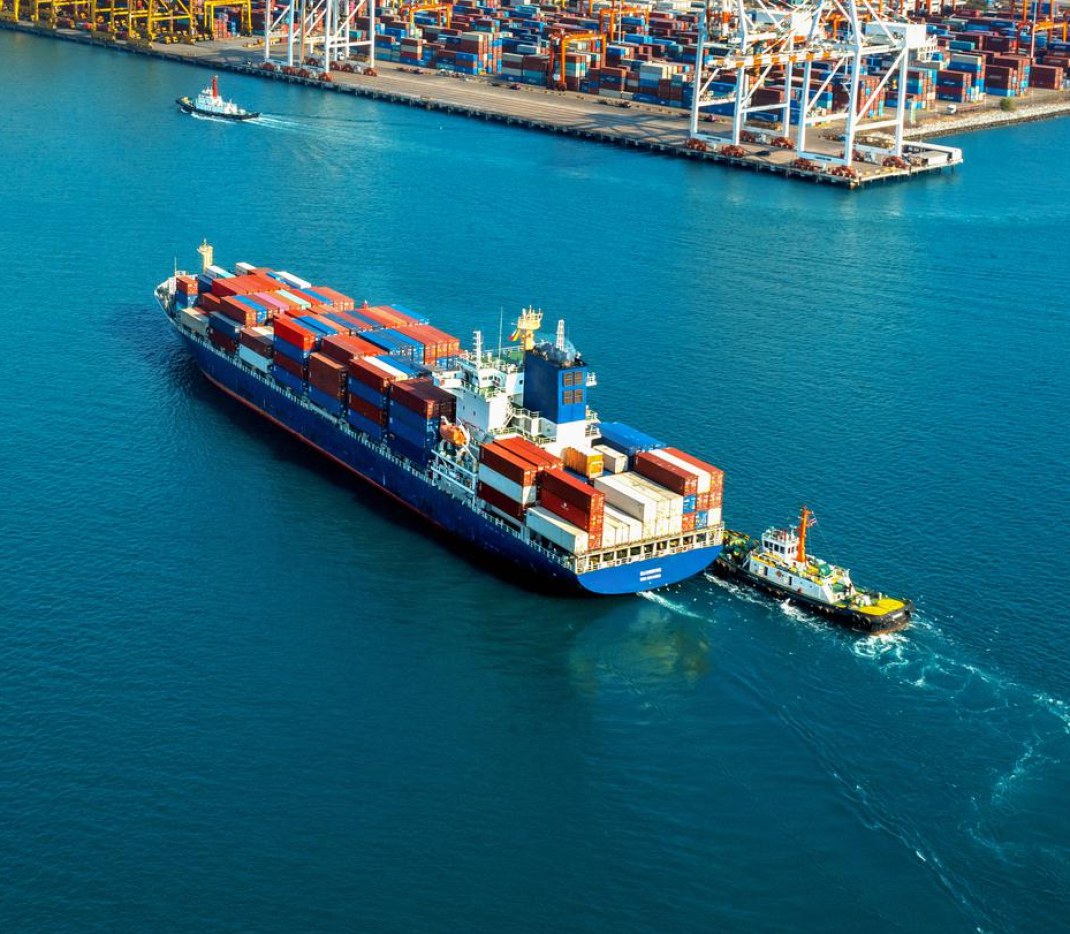 A container vessel being manoeuvred into port by a tug
